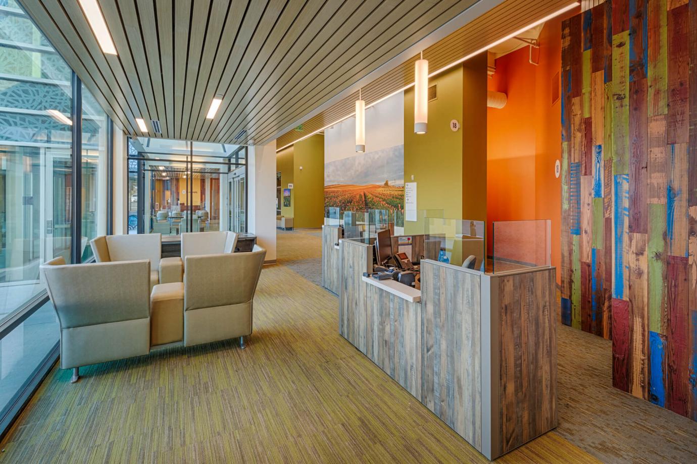 To the right from the large flower mural at the entry lobby, is the weathered wood reception desk with colorful reclaimed wood wall behind